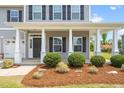 Home's front porch features white columns, a gray front door, and landscaping at 33 E Ravano Dr, Clayton, NC 27527