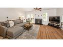 Cozy living room featuring a gray sectional, fireplace, and hardwood flooring, creating a comfortable and stylish space at 4604 Townesbury Ln, Raleigh, NC 27612