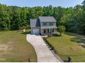 Aerial view of a two-story home with large yard, long driveway, and a playset in a wooded area at 486 S Denise Ave, Coats, NC 27521