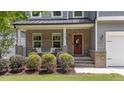 Inviting front porch with brick accents, a red door, and manicured landscaping at 516 Culmore Dr, Fuquay Varina, NC 27526