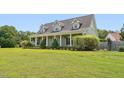 Traditional exterior featuring a large front lawn, inviting porch, and stately columns at 5405 Overdale Ln, Raleigh, NC 27603
