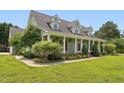 Charming exterior featuring a covered front porch, green paint, white columns, and manicured landscaping at 5405 Overdale Ln, Raleigh, NC 27603