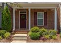 Inviting front porch featuring brick facade, decorative wreath, and lush landscaping, perfect for a cozy welcome at 5908 Giddings St, Raleigh, NC 27616