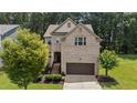 Two-story brick home featuring an attached garage, manicured lawn and mature trees at 8132 Wheeler Woods Dr, Apex, NC 27539