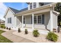 A close-up showcases a covered porch with flowers and white columns in front of home with blue shutters at 820 Water Plant Rd, Zebulon, NC 27597