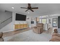 Open-concept living room with ceiling fan flows into modern kitchen with island and light wood flooring at 820 Water Plant Rd, Zebulon, NC 27597