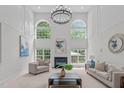 Bright living room features a fireplace, large windows and high ceilings with modern chandelier at 101 Quarryrock Rd, Holly Springs, NC 27540