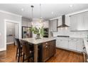 Open kitchen with a granite island, stainless steel appliances, hardwood floors, and stylish pendant lighting at 105 Everam Ct, Chapel Hill, NC 27516