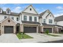 Modern townhouses featuring white siding, gray brick, black accents, and landscaping create an appealing facade at 109 Periwinkle Pl, Clayton, NC 27527