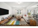 This bright living room has hardwood floors, modern furniture, a patterned rug, and large windows at 109 Periwinkle Pl, Clayton, NC 27527