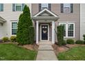 Inviting townhome entrance featuring a black door, tasteful wreath, and well-maintained landscaping at 1108 Renewal Pl, Raleigh, NC 27603