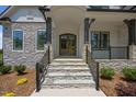 Stone steps leading to an elegant front door with black railing and stone pillars at 111 Stone Park Dr, Wake Forest, NC 27587