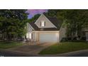 Charming home featuring neutral siding, a two-car garage, and well-maintained landscaping at dusk at 206 Lake Brandt Dr, Cary, NC 27519