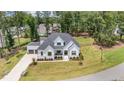 Aerial view of a modern farmhouse home with a landscaped yard and a driveway leading to an attached three-car garage at 2328 Sanctuary Dr, Raleigh, NC 27606