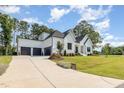 Long driveway leading to a modern farmhouse with three-car garage, lush lawn, and mature trees at 2328 Sanctuary Dr, Raleigh, NC 27606