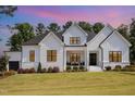 Charming white brick home with modern black-framed windows and covered porch, set against a colorful sky at 2328 Sanctuary Dr, Raleigh, NC 27606
