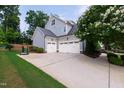Three-car garage with white doors, ample driveway space, and a basketball hoop, great for activities at 2661 Silver Bend Dr, Apex, NC 27539