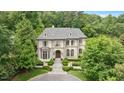 Stately stone home with mature trees, symmetrical design, arched windows, and circular driveway at 3347 Alamance Dr, Raleigh, NC 27609