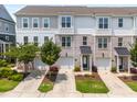 Three-story townhomes showcasing gray, white, and brick exteriors, small trees, and driveways leading to garages at 364 Skymont Dr, Holly Springs, NC 27540