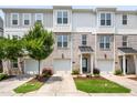 Three-story townhomes showcasing gray, white, and brick exteriors, small trees, and driveways leading to garages at 364 Skymont Dr, Holly Springs, NC 27540