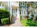 Inviting two-story townhome with a charming front porch, lush greenery, and a well-manicured lawn at 408 Heritage Village Ln, Apex, NC 27502