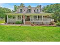 Inviting front of home with a covered porch, green grass, and beautiful landscaping at 4702 Pleasant Green Rd, Durham, NC 27705