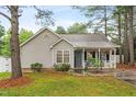 Inviting single-story home with a quaint front porch and a well-maintained lawn surrounded by mature trees at 50 Rainwood Ct, Louisburg, NC 27549