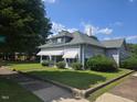 Traditional two-story home with a cozy covered front porch and mature trees in the front yard at 500 W Main St, Benson, NC 27504