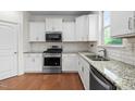 Well-lit kitchen with granite countertops, stainless steel appliances, white cabinetry, and a subway tile backsplash at 817 Stable Fern Dr, Fuquay Varina, NC 27526