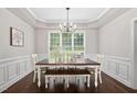 Elegant dining room with chandelier, wainscoting, and large window at 8201 Ivymount Way, Raleigh, NC 27613
