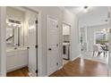 Hallway with a view of a half bathroom and a laundry room, with hardwood floors and white trim at 8912 Erinsbrook Dr, Raleigh, NC 27617