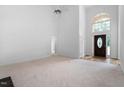 Spacious living room with carpet, soaring ceilings, a ceiling fan, and a decorative glass front door at 101 Deerwalk Ct, Cary, NC 27513