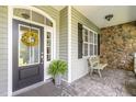 Covered porch featuring stone accents, bench seating, and stylish front door at 109 Jasmine Rose Ct, Holly Springs, NC 27540