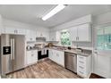Bright kitchen with stainless steel appliances, white cabinets, and wood-look floors at 1209 Lochcarron Ln, Cary, NC 27511
