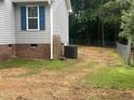 Rear exterior featuring gray vinyl siding, red brick crawlspace facade, and a fenced yard with mature trees at 125 Tast Dr, Wendell, NC 27591
