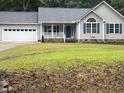 Charming single-story home featuring a blue front door, gray siding, and an attached two-car garage at 125 Tast Dr, Wendell, NC 27591