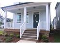 Inviting front porch with white railings, wooden steps, and a stylish blue front door at 1534 Millrock Trl, Wendell, NC 27591