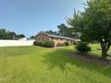 Well-maintained brick home featuring manicured landscaping, a fenced yard and mature trees at 202 Camelia Dr, Princeton, NC 27569
