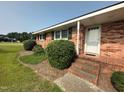 Close up of a brick home's entrance, showing steps, landscaping, and a storm door at 202 Camelia Dr, Princeton, NC 27569