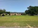 Traditional brick home with a large front yard, mature trees, and a covered side carport at 202 Camelia Dr, Princeton, NC 27569