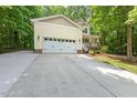 Wide driveway leading to a yellow two-story home with an attached garage nestled amongst trees at 2721 Rustic Brick Rd, Raleigh, NC 27603