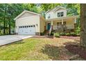 Inviting two-story yellow home with a charming porch, a well-maintained lawn, and attached garage at 2721 Rustic Brick Rd, Raleigh, NC 27603