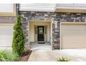 Close-up of the home's entrance, featuring a stone facade, black front door, and one-car garage at 3015 Cypress Lagoon Ct, Durham, NC 27703