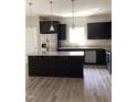 Modern kitchen with stainless steel appliances, dark cabinetry, granite countertops, and a center island at 305 Theys Mill, Fuquay Varina, NC 27526