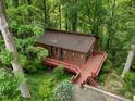 Aerial view of a brown two-story house surrounded by lush greenery and featuring a large wooden deck at 3416 Ocotea St, Raleigh, NC 27607