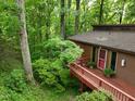 Secluded brown two-story home featuring an expansive wooden deck and lush, mature trees surrounding the property at 3416 Ocotea St, Raleigh, NC 27607