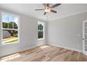 Bright bedroom with light wood floors, two windows, a ceiling fan, and fresh, neutral paint at 4896 Grosbeak Ct, Mebane, NC 27302