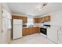 Functional kitchen with wooden cabinets and white appliances, including a washer and dryer for convenience at 555 Dacian Rd, Raleigh, NC 27610