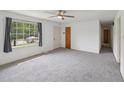 Bright living room featuring new carpeting, a ceiling fan, and a large window providing ample natural light at 555 Dacian Rd, Raleigh, NC 27610