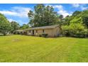 Side angle of brick home with a green yard and mature trees in a quiet neighborhood at 605 Sexton Ave, Zebulon, NC 27597